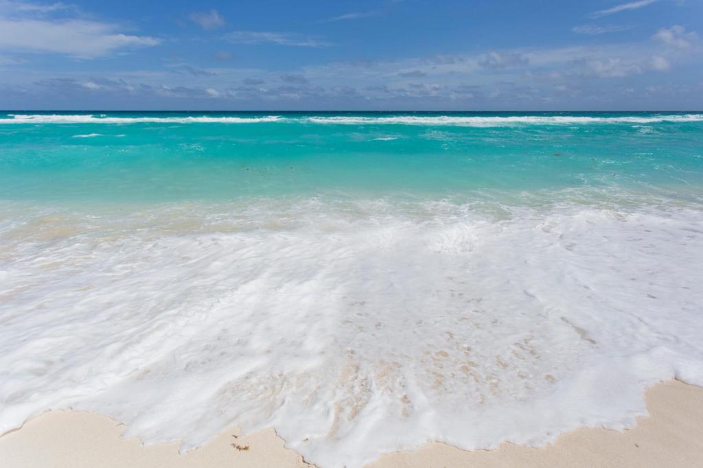 uma praia de areia com o oceano e água azul em Large House - walking to beach - 10 guests! em Cancún
