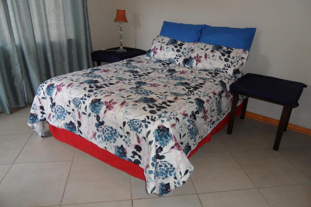 a bedroom with a bed with a blue and white blanket at Rosy Palm Sunrise in Upington