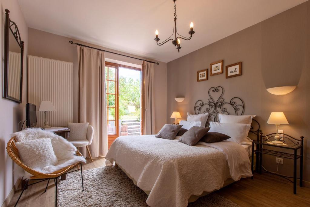 a bedroom with a bed and a chair and a window at Hotel Kieffer in Itterswiller