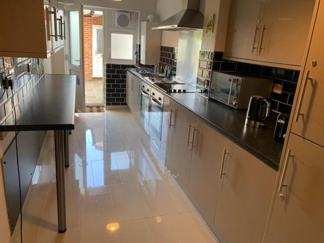 a large kitchen with white cabinets and black counter tops at Serviced Accommodations in Luton