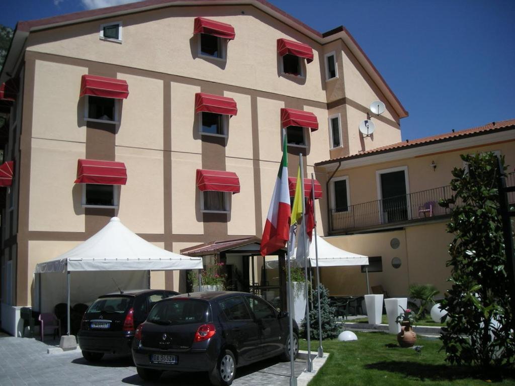 two cars parked in front of a large building at Hotel de Meis in Capistrello