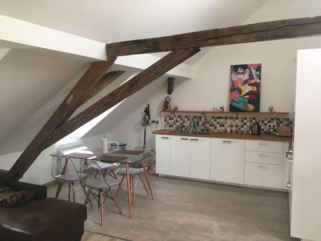 een keuken met witte kasten en een tafel met stoelen bij Belles combles alsaciennes au centre de Strasbourg in Straatsburg