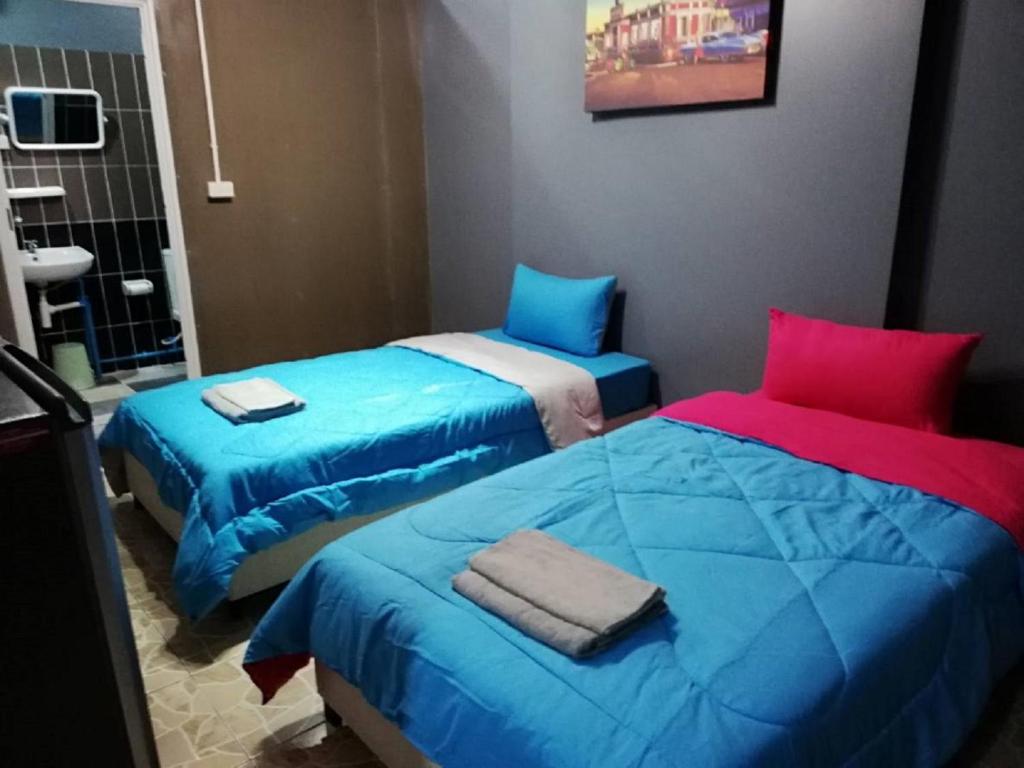 two beds in a room with blue and red pillows at E2S Place in Nakhon Nayok
