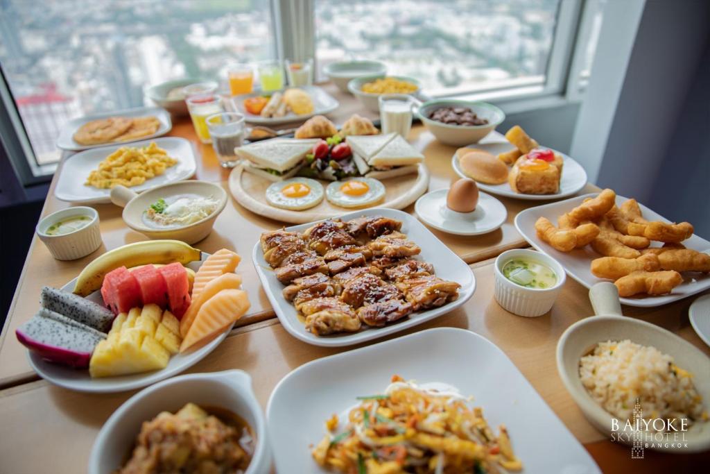 A generous breakfast spread arranged beside large windows overlooking the city.