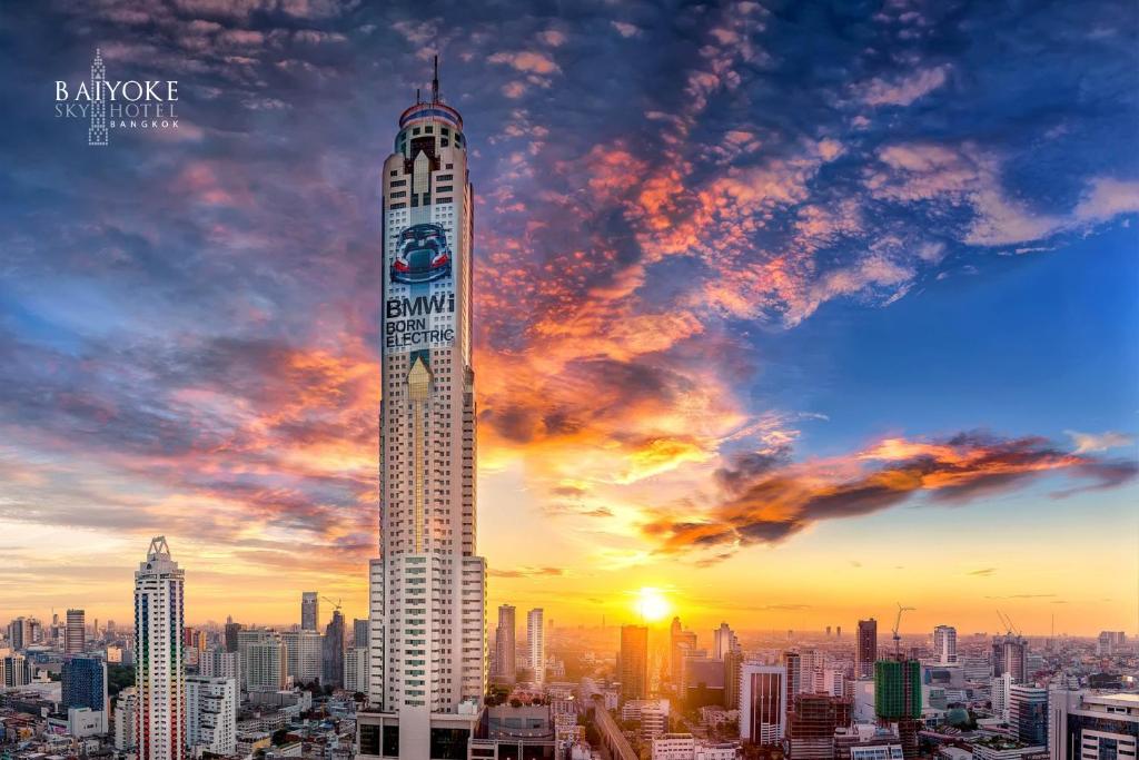 een hoog gebouw met een zonsondergang in de lucht bij Baiyoke Sky Hotel in Bangkok