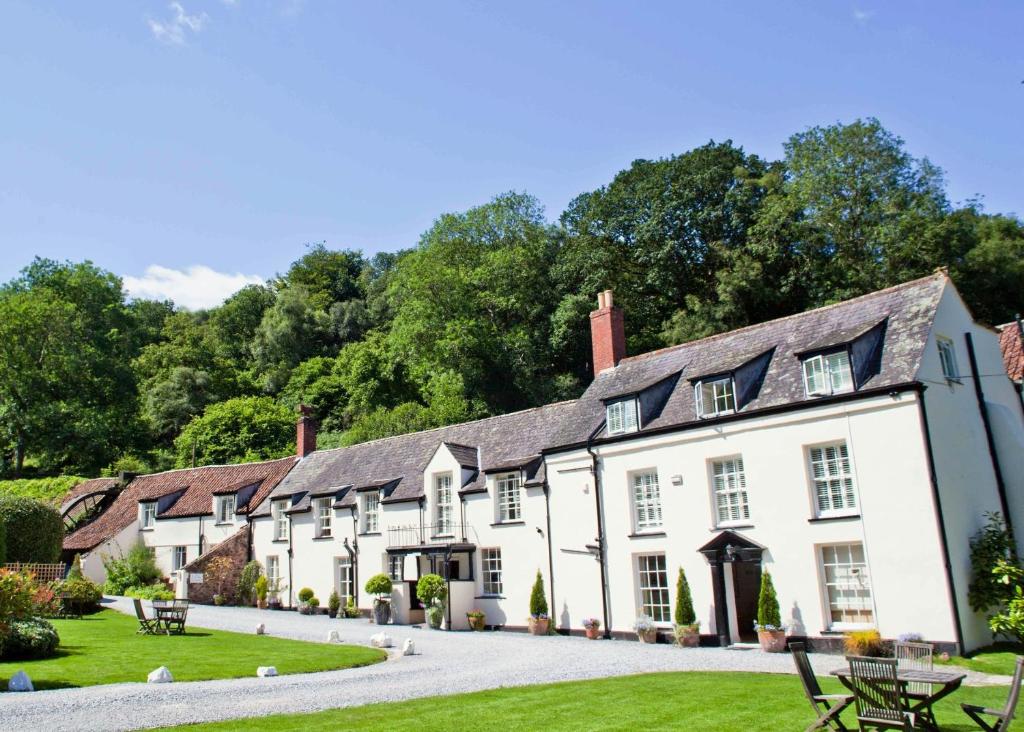 a row of white buildings with trees in the background at Combe House Hotel in Holford