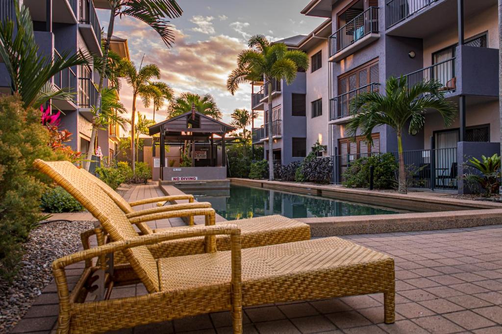 a couple of chairs sitting next to a swimming pool at Southern Cross Atrium Apartments in Cairns