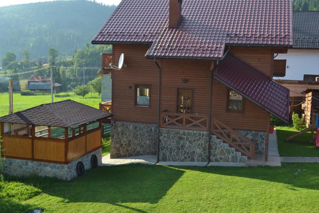 uma grande casa de madeira com um portão e um quintal em Aura Karpat em Bukovel