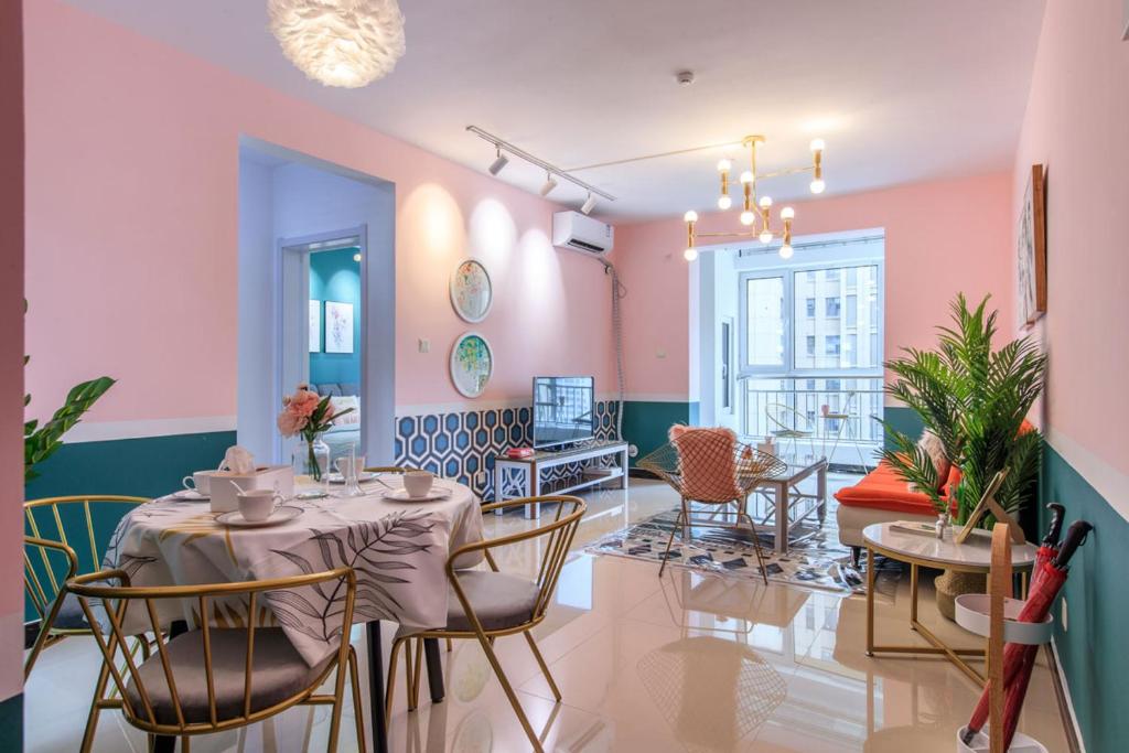 a dining room with pink walls and a table and chairs at Baoding Lianchi·Baoding East Station· Locals Apartment 00163450 in Baoding