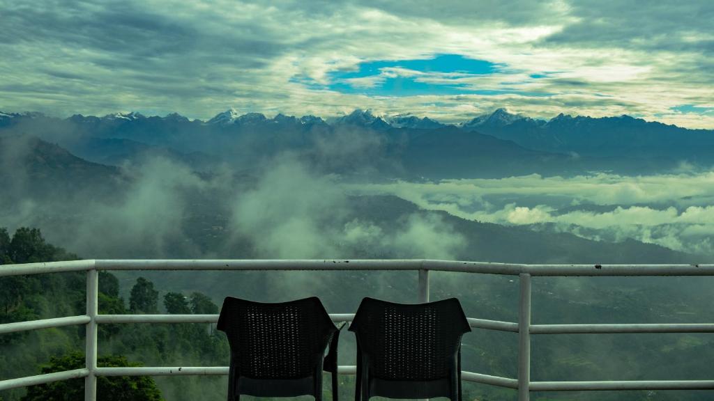 two chairs sitting on a balcony looking at the mountains at Mount Princess Hotel in Dhulikhel