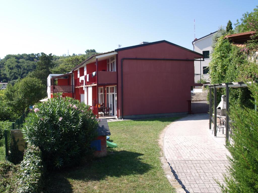 een rood gebouw met een garage in een tuin bij Apartments Lavanda Fiesa in Piran