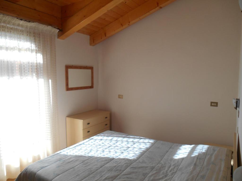 een slaapkamer met een bed en een raam bij Chalet Migazzi - mansarda in Cogolo