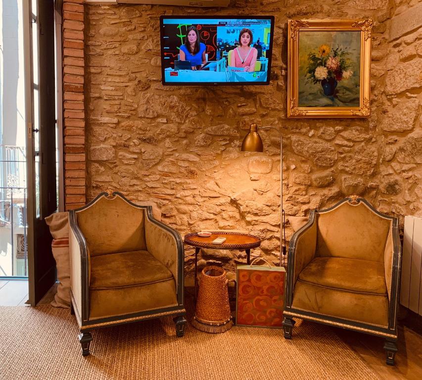 2 sillas en una habitación con TV en una pared de piedra en Bravissimo Old Side Girona One, cozy apartment, en Girona