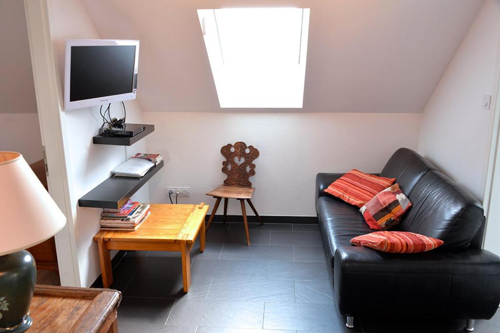 a living room with a black leather couch and a table at Gites Chez Schangala in Thannenkirch