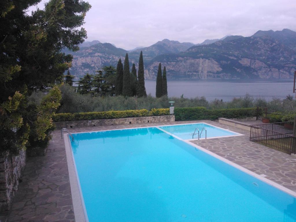 a large blue swimming pool with a view of a lake at Appartamento Perla del Lago - Enchanting Lake View in Malcesine