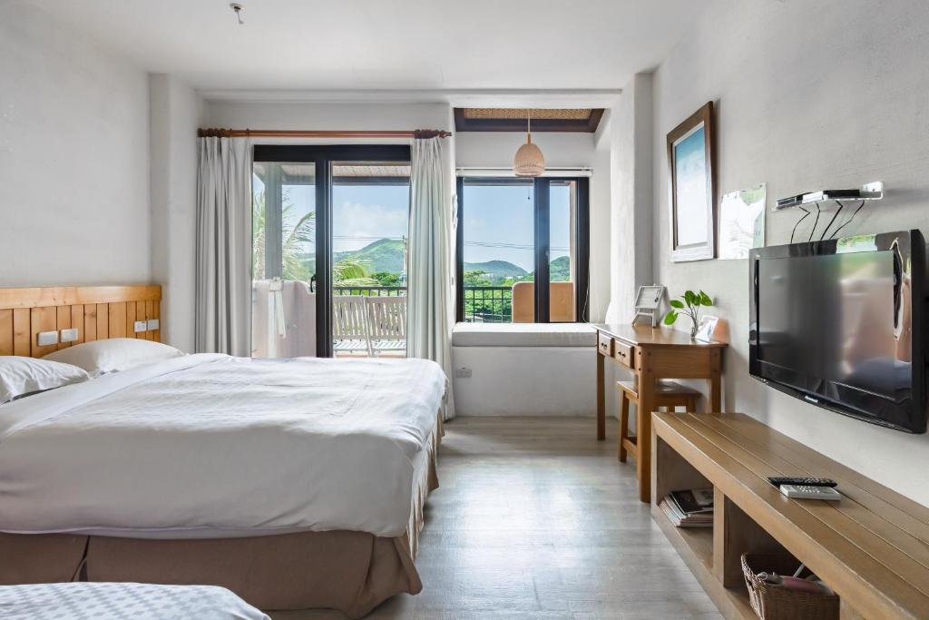 a hotel room with two beds and a television at Fairyland &amp; Farm Guest House in Kenting