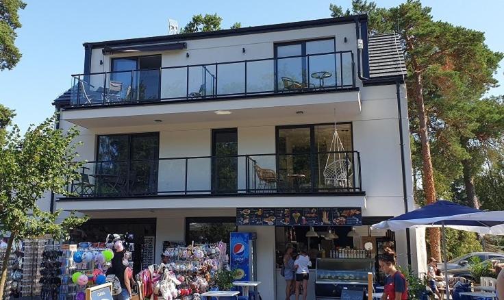 a large white building with a balcony on top of it at Apartamenty Aqua in Pobierowo