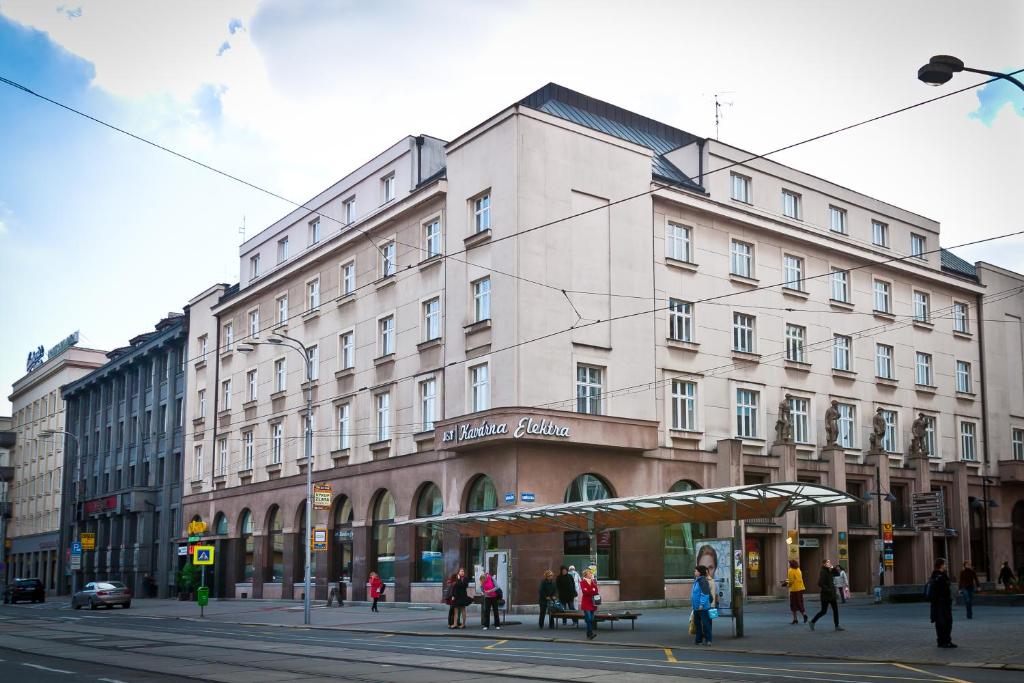 duży biały budynek na ulicy miejskiej z ludźmi w obiekcie Hotel Palác Elektra w Ostravie