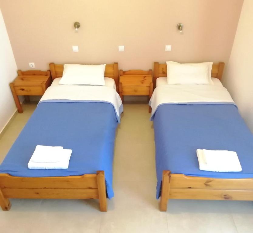 two beds in a room with blue and white sheets at Hotel Thisvi in Stalís