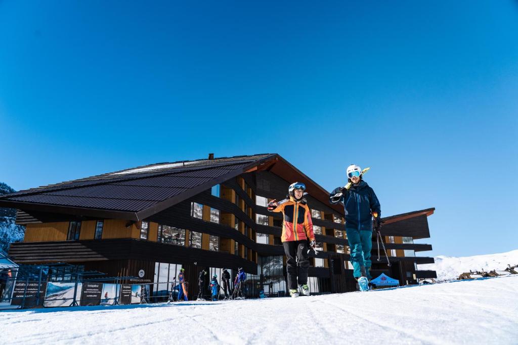 two people standing in the snow in front of a ski lodge at Myrkdalen Resort Hotel in Myrkdalen