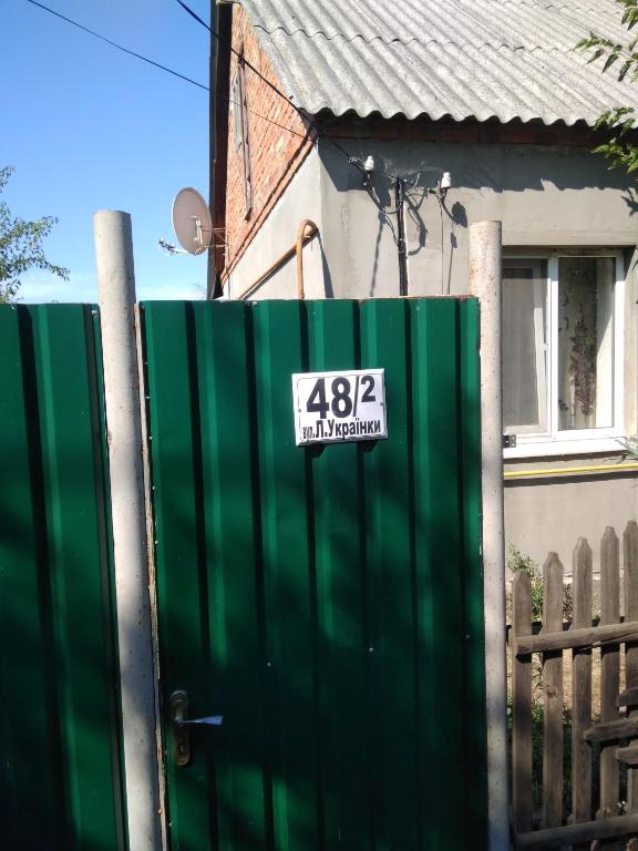 a green fence with a sign on it in front of a house at Дом in Okhtyrka