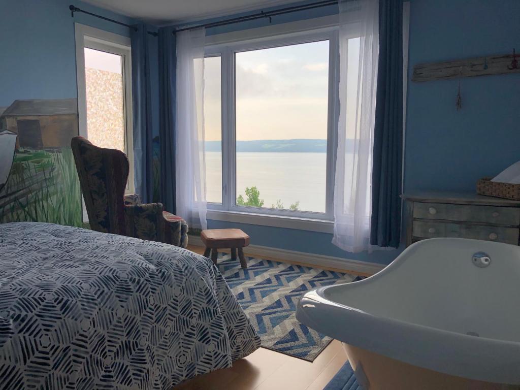 1 dormitorio con cama, bañera y ventana en Suite 1, Flèche du fjord, vue Saguenay, Mont Valin, en Saint-Fulgence