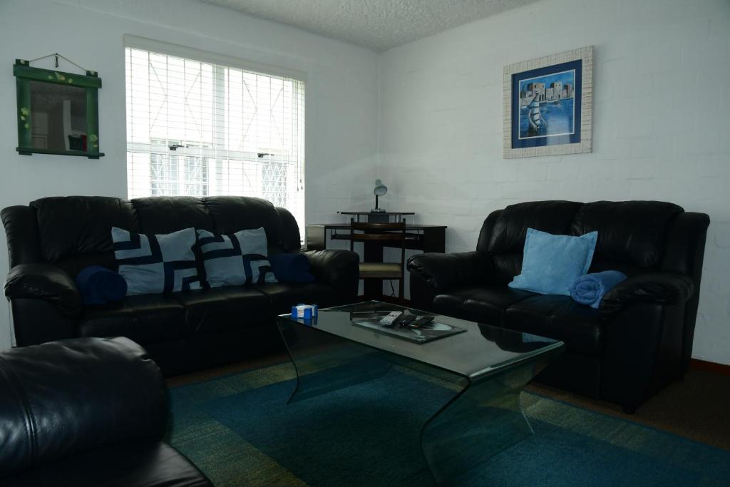 Sala de estar con 2 sillas de cuero y mesa de centro en Bradclin @ York, en Ciudad del Cabo