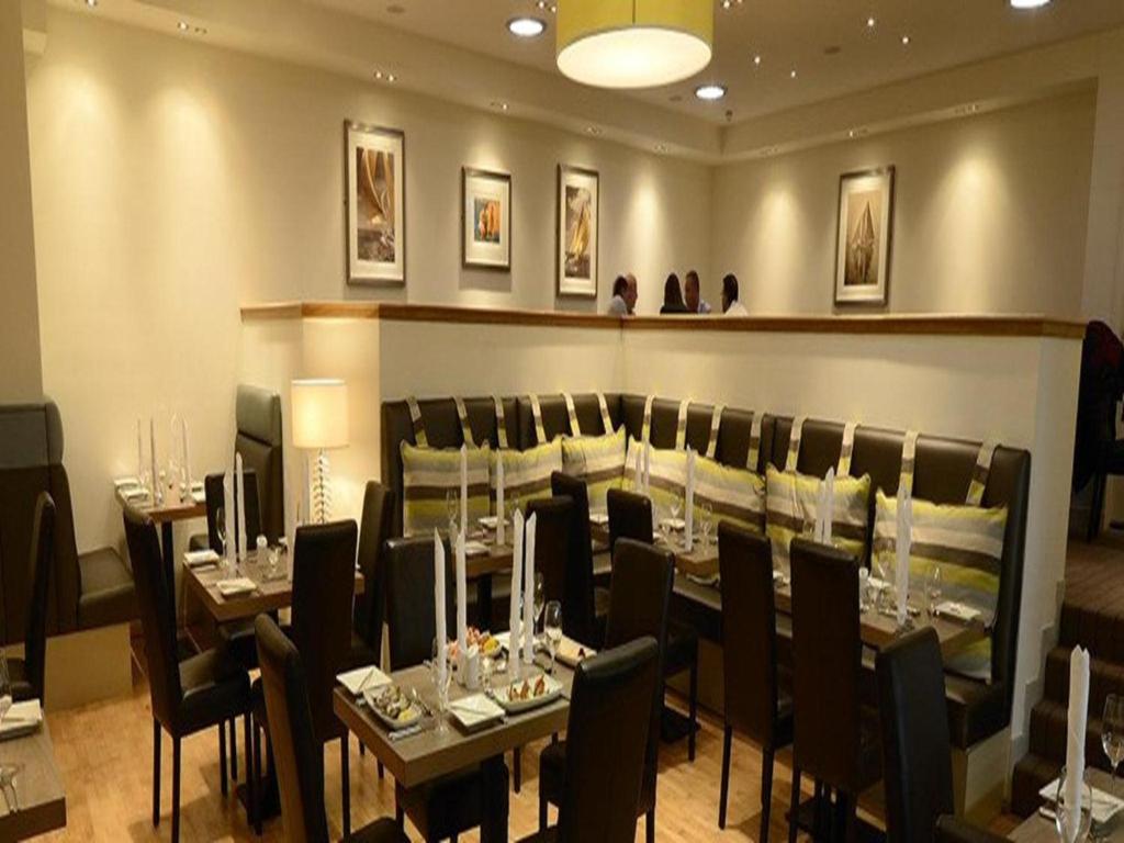 a restaurant with tables and chairs in a room at Anchor Hotel and Seabed Restaurant in Tarbert