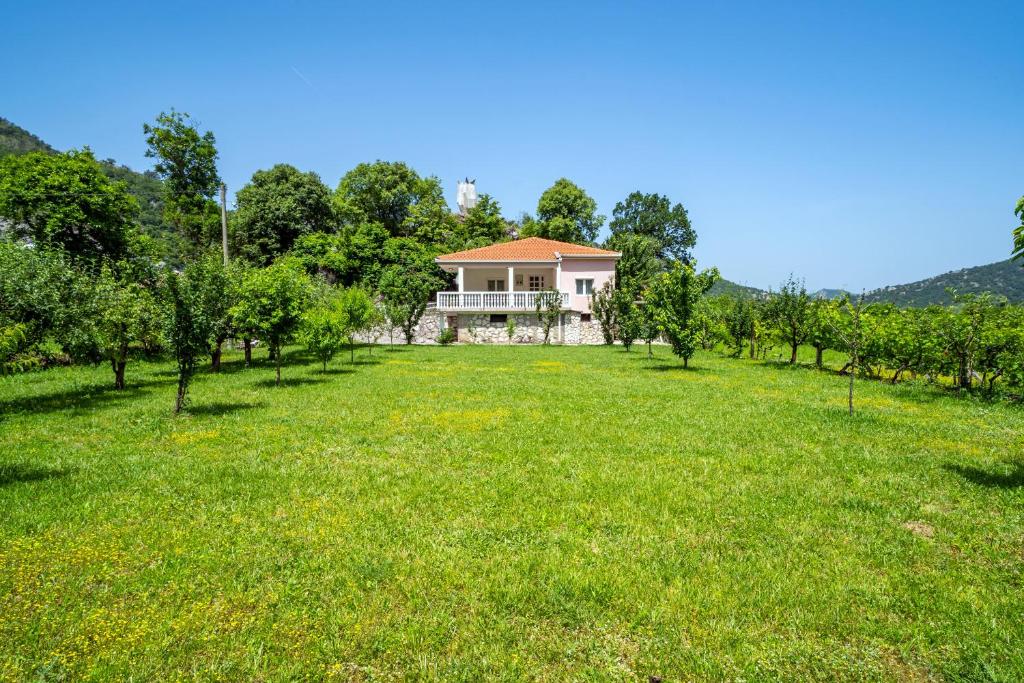 a large grassy field with a house in the background at House Gorica in Bar