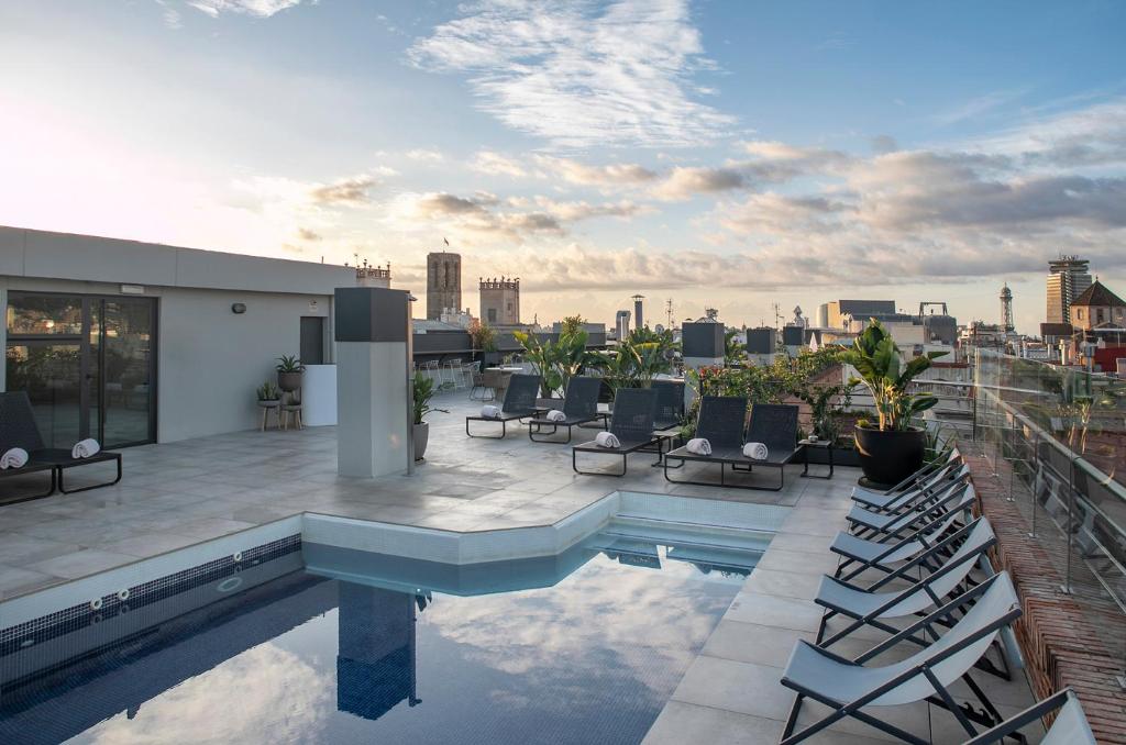 a rooftop patio with chairs and a pool on a building at Silken Ramblas in Barcelona