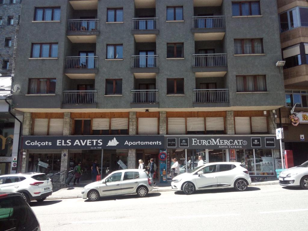 um edifício alto com carros estacionados em frente em Apartaments Els Avets em Pas de la Casa