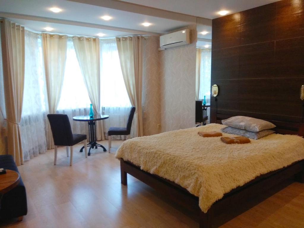 Apartment on Dubenskaya street في روفنو: غرفة نوم بسرير وطاولة مع كراسي
