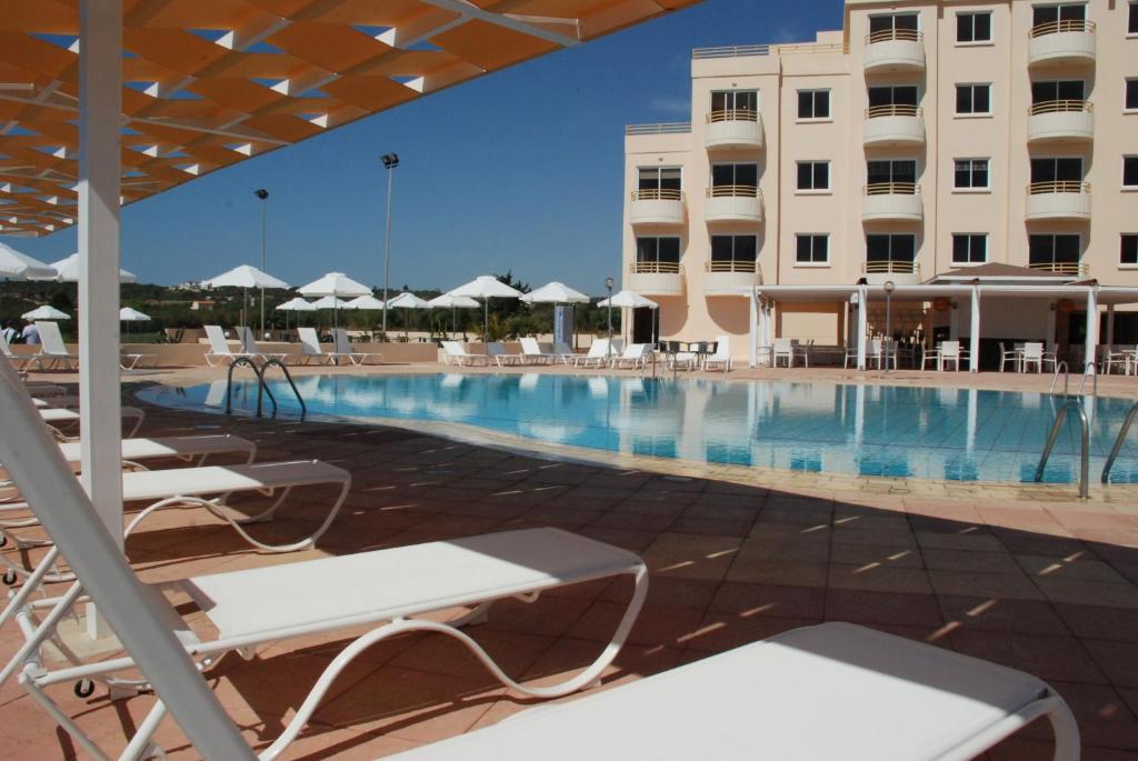 una piscina en un hotel con sillas y un edificio en Kama Lifestyle Apartments, en Protaras