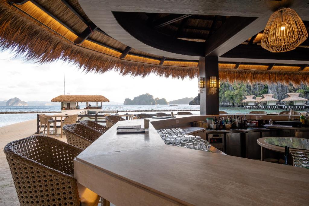 a restaurant with a bar with a view of the ocean at El Nido Resorts Miniloc Island in El Nido