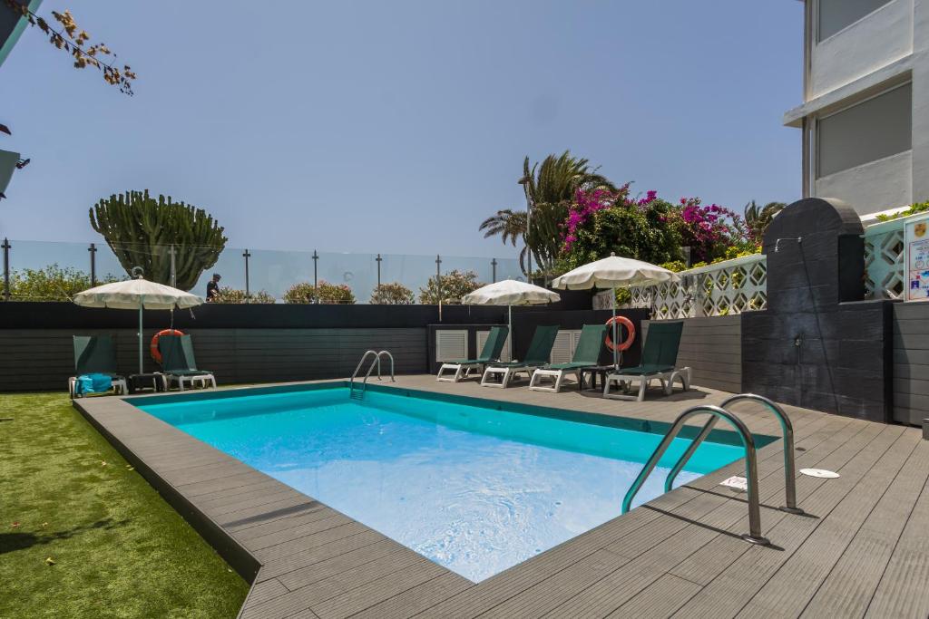een zwembad met stoelen en parasols op een huis bij Alsol Patricio in Playa del Inglés