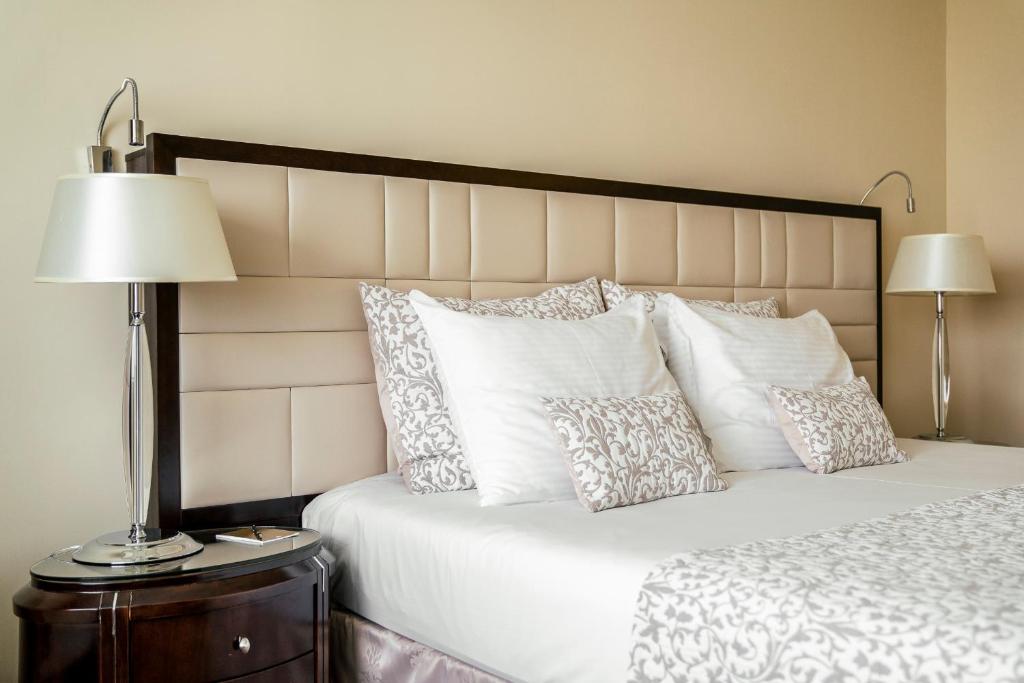 a bedroom with a white bed with pillows and a lamp at Baltic Beach Hotel & SPA in Jūrmala