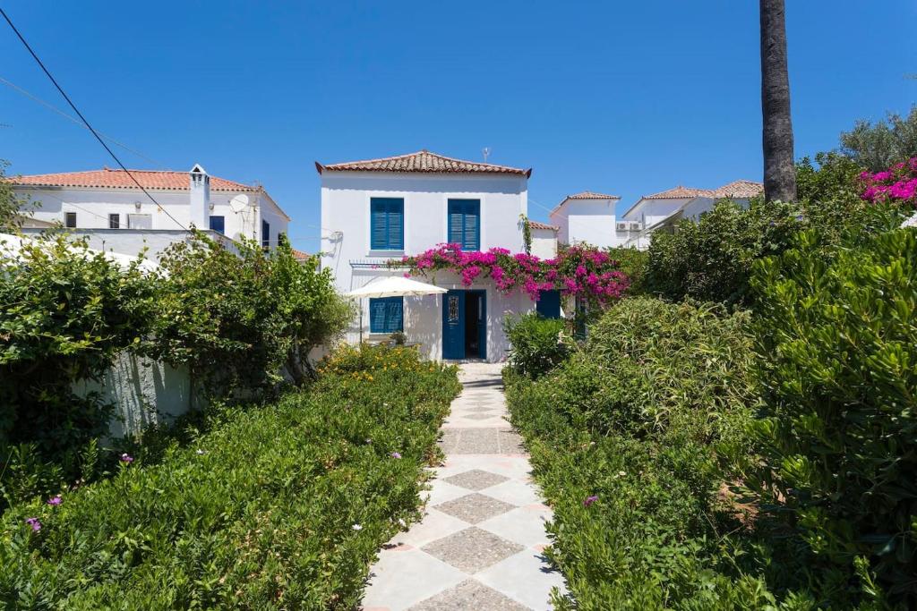 a pathway in front of a white house with pink flowers at The Palm Tree House!! in Spetses