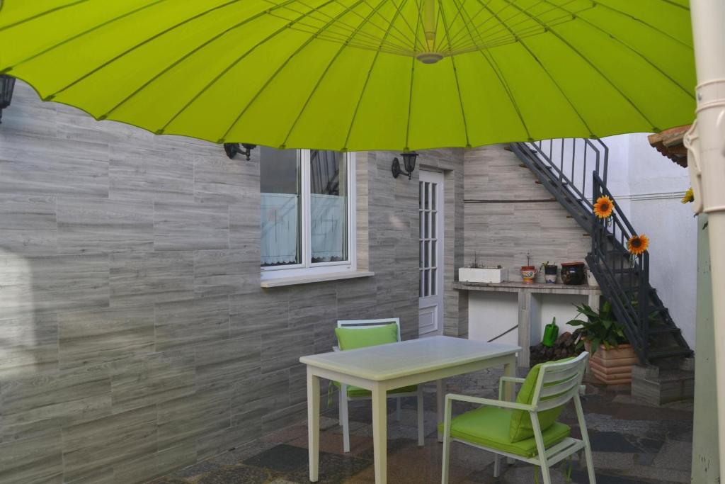 einen Tisch und Stühle unter einem grünen Sonnenschirm auf einer Terrasse in der Unterkunft MENCIA in Mansilla de las Mulas