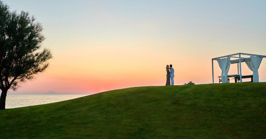 a couple standing on top of a hill at sunset at Capovaticano Resort Thalasso Spa in Capo Vaticano