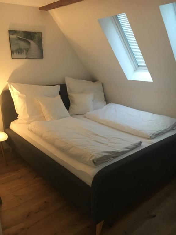 1 cama con sábanas blancas y almohadas en una habitación en Gästehaus an der Frauenkirche, en Günzburg