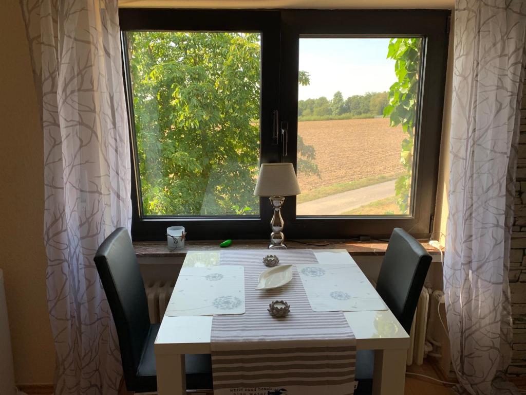 a table with chairs and a window with a view of a field at Ferienwohnung am Bramschebach in Löhne