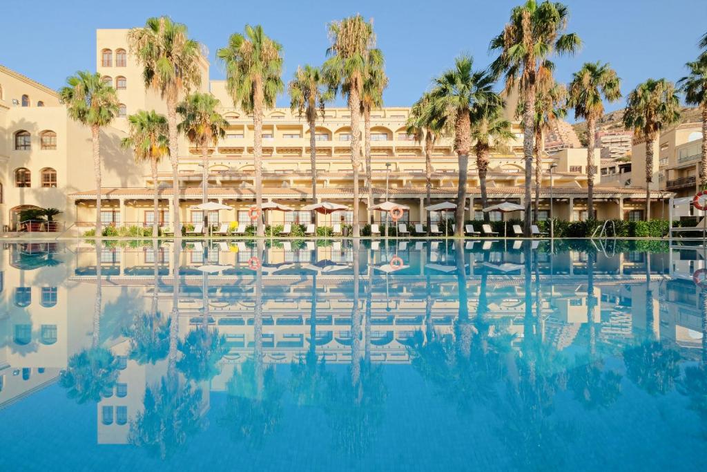 a view of a hotel with palm trees and a swimming pool at Hotel Envia Almería Spa & Golf in Aguadulce