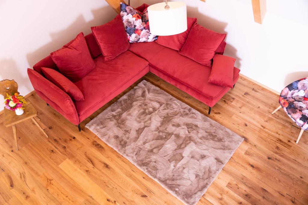 a red couch with red pillows in a living room at Teichwiesn in Sankt Stefan ob Stainz