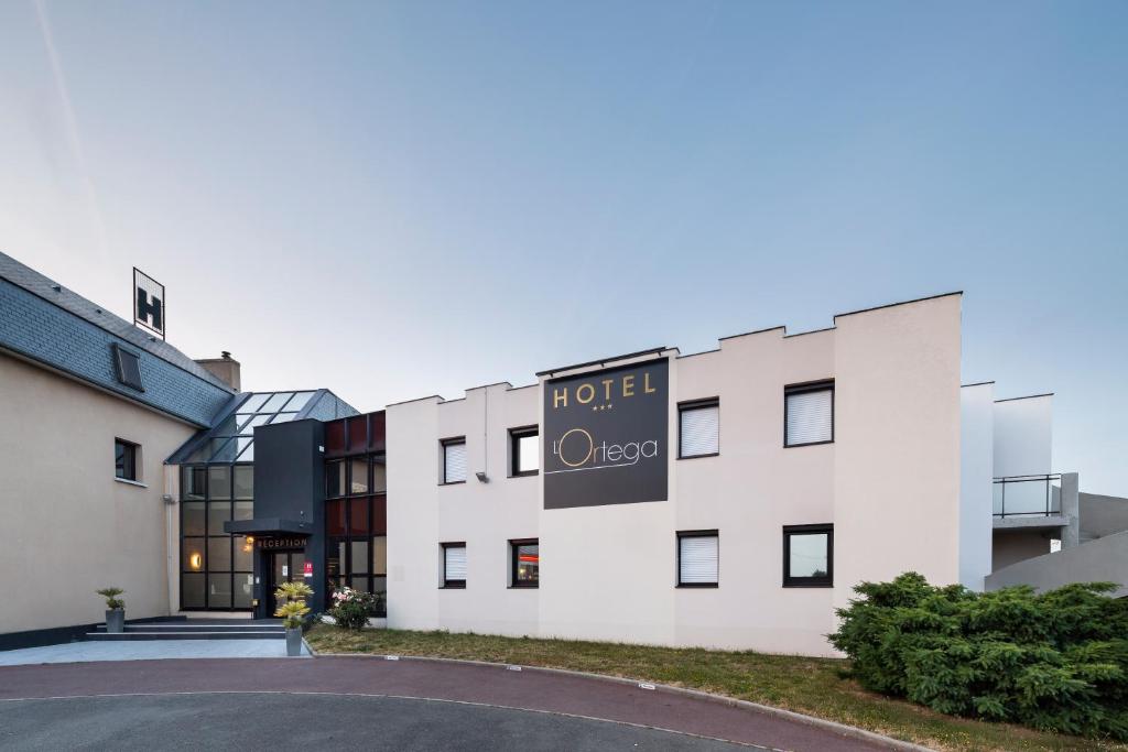 hotel z znakiem na boku budynku w obiekcie Hotel L'Ortega Rennes Aéroport w mieście Saint-Jacques-de-la-Lande