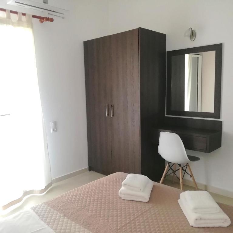 a bedroom with a bed and a chair and a mirror at Hotel Thisvi in Stalís