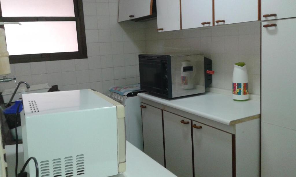 a kitchen with a microwave and a refrigerator at Residencial flat Golden beach.. in Guarujá