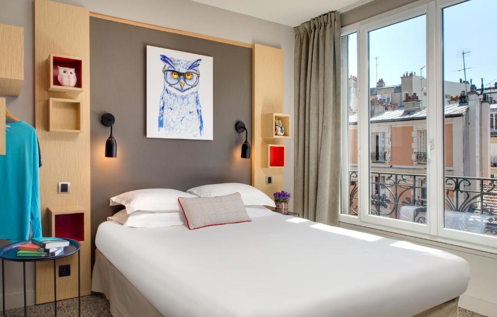 een slaapkamer met een groot wit bed en een raam bij Chouette Hotel in Parijs