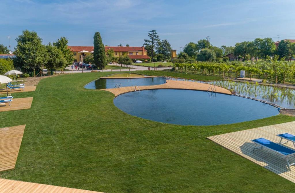 a swimming pool in the middle of a grass field at Agriturismo Tenuta Regina - Glamping luxury lodges and apartments in Palazzolo dello Stella