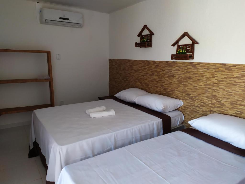 a bedroom with two beds and a brick wall at Recanto das Folhas in Paripueira