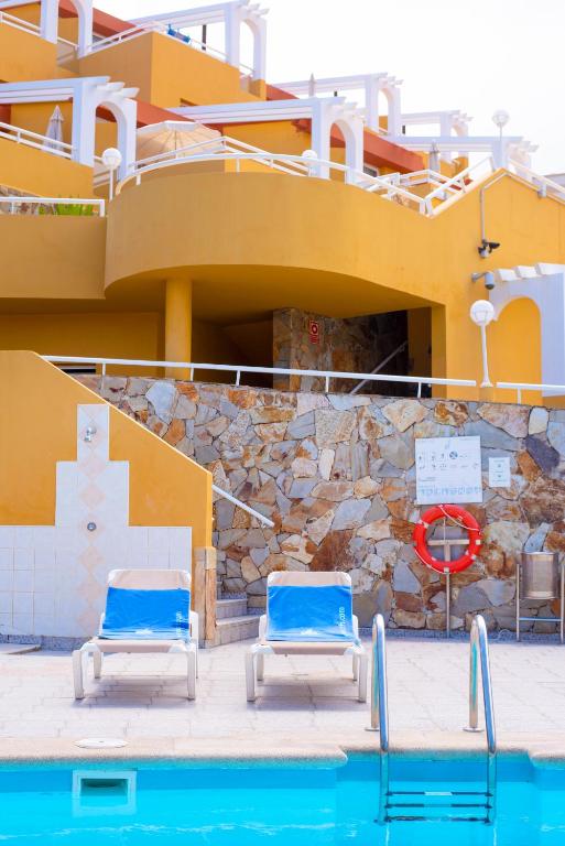 two blue chairs sitting next to a swimming pool at Apartamentos Punta Marina by LIVVO in Morro del Jable